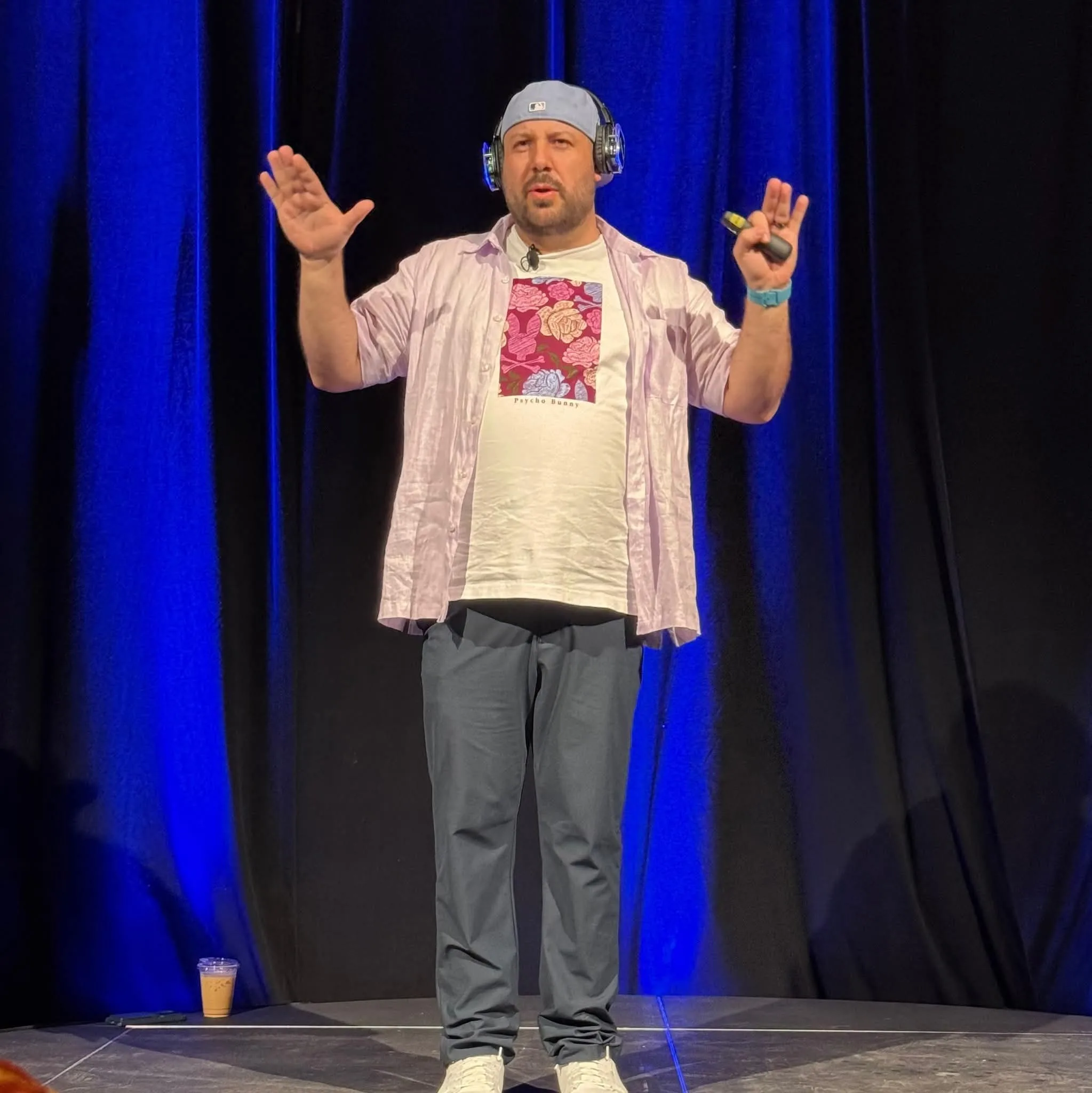 Ron Capalbo speaking onstage with a headset and presentation clicker