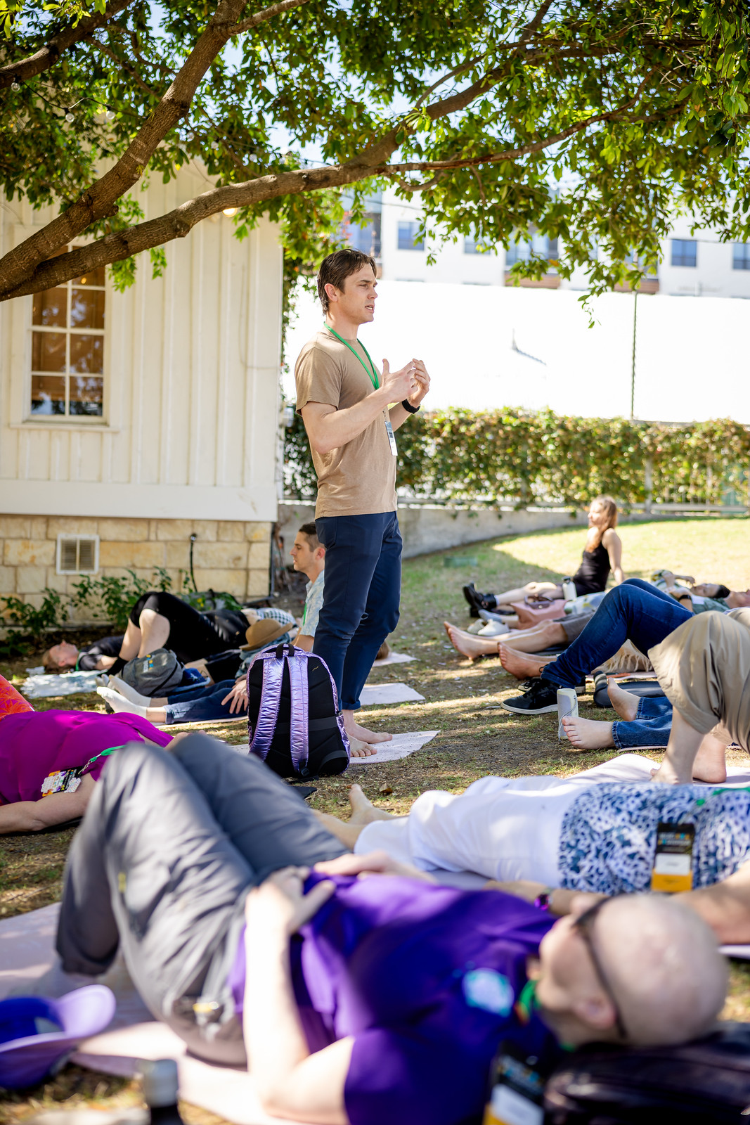Attendees lie on mats under a tree during an outdoor movement session at NeuroDiversion 2026 in Austin.